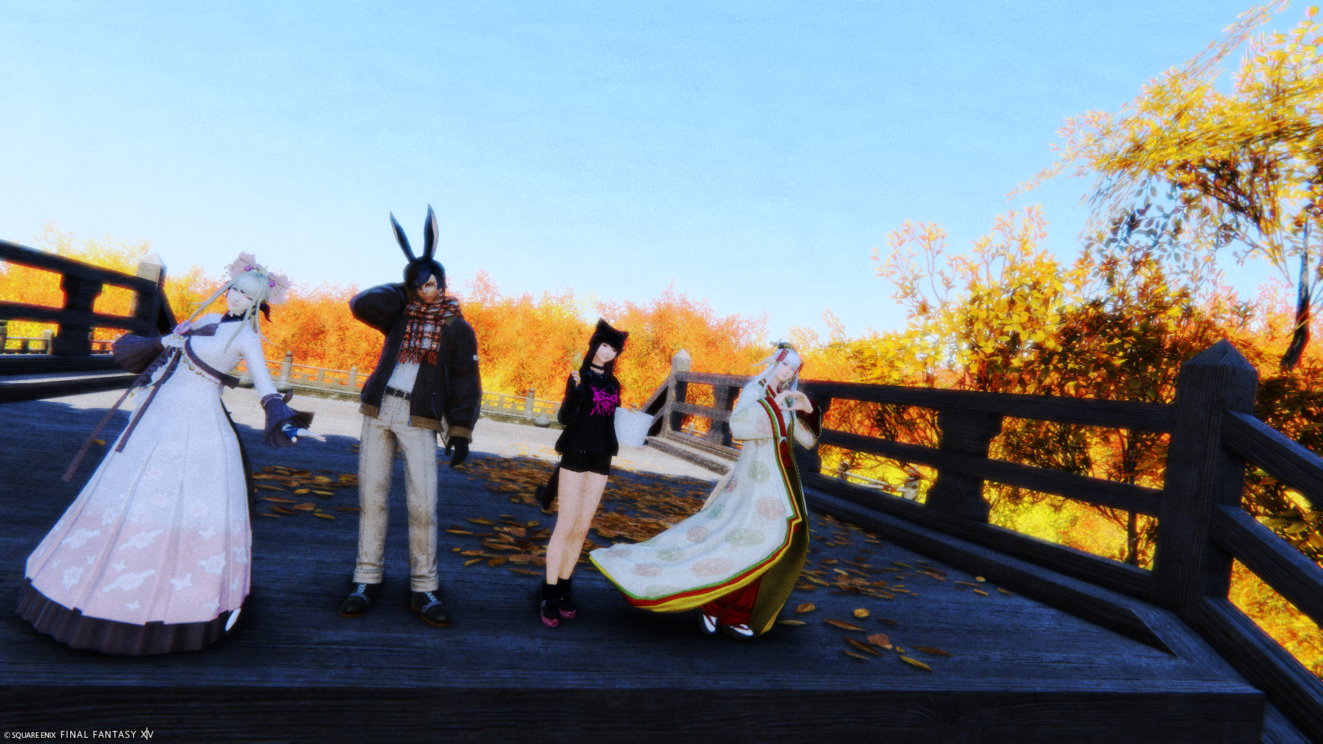 Auto-generated description: 4人のファンタジーキャラクターが秋の景色の中で木の橋に立っている。