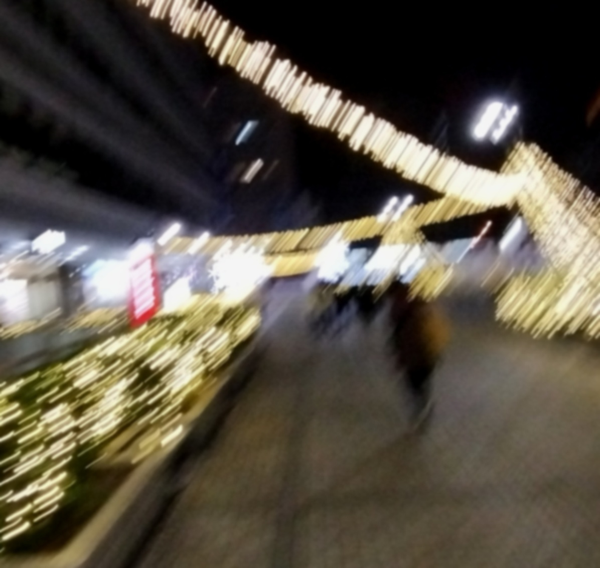 Auto-generated description: 夜の街で、たくさんのイルミネーションが施された通りを人々が歩いています。