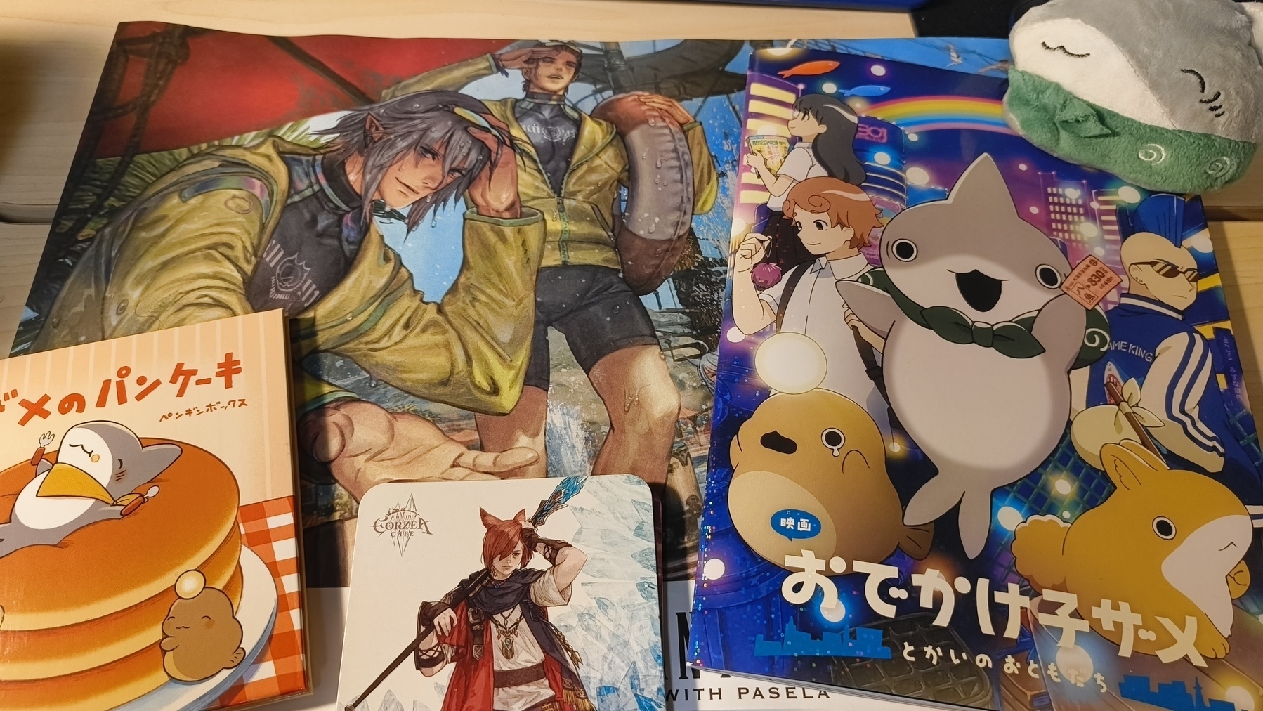 Auto-generated description: 机の上にゲームやアニメ関連のグッズが複数置かれており、ぬいぐるみも見えます。