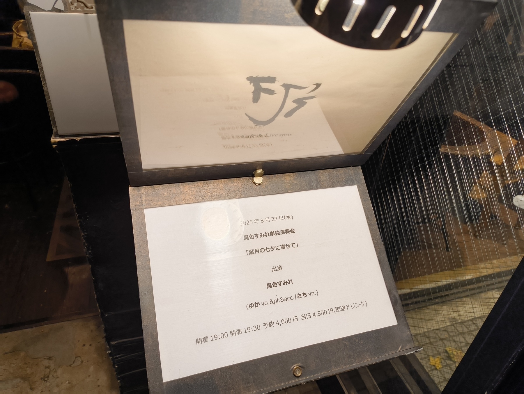 Auto-generated description: ランプの下に和風の看板があり、営業時間や料金に関する情報が書かれた紙が掲示されている。