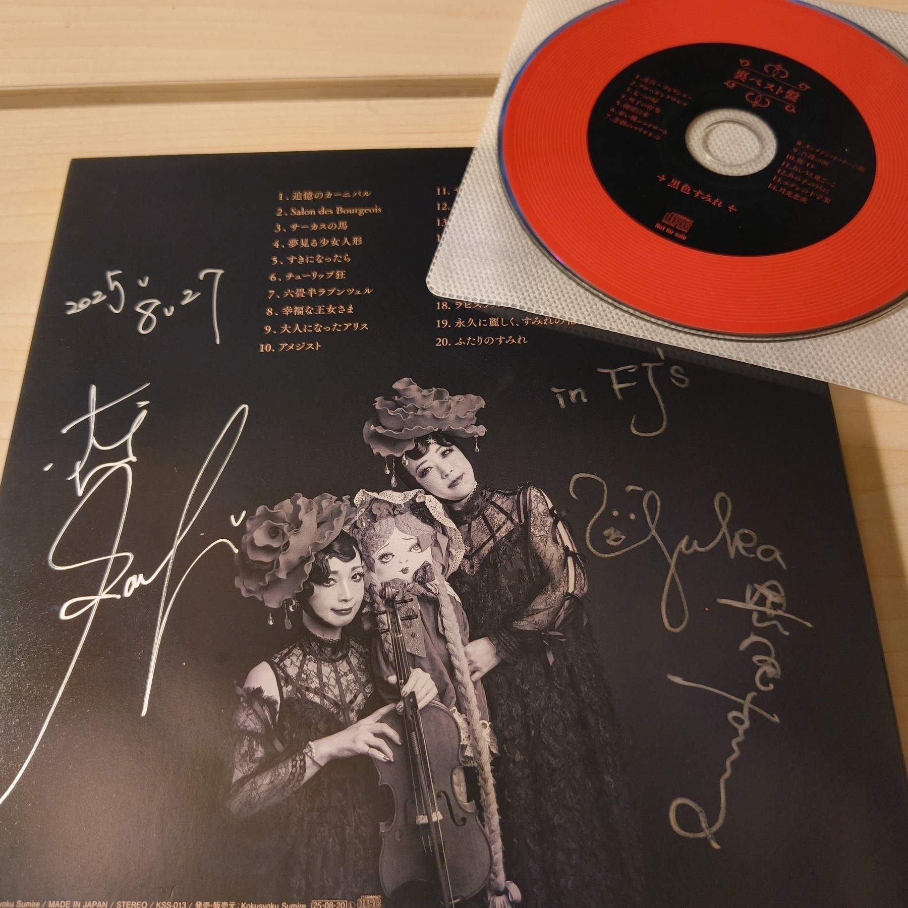 Auto-generated description: 黒いドレスを着た3人の女性の写真があるレコードアルバムカバーと赤いCD。