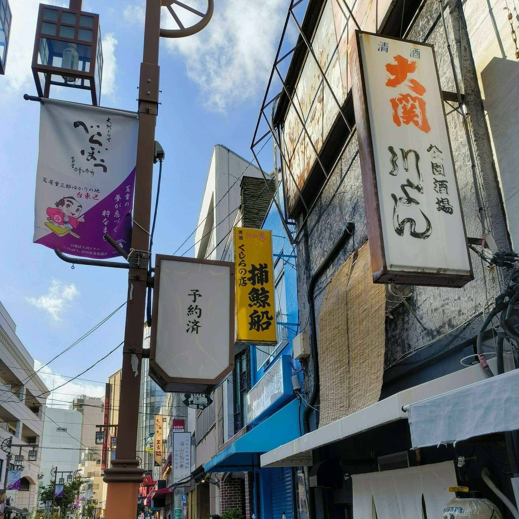 浅草の路地に並ぶ居酒屋の看板群。名店「捕鯨船」の黄色い看板と、たけしさんのために空けてあるという「予約済」の看板が印象的。