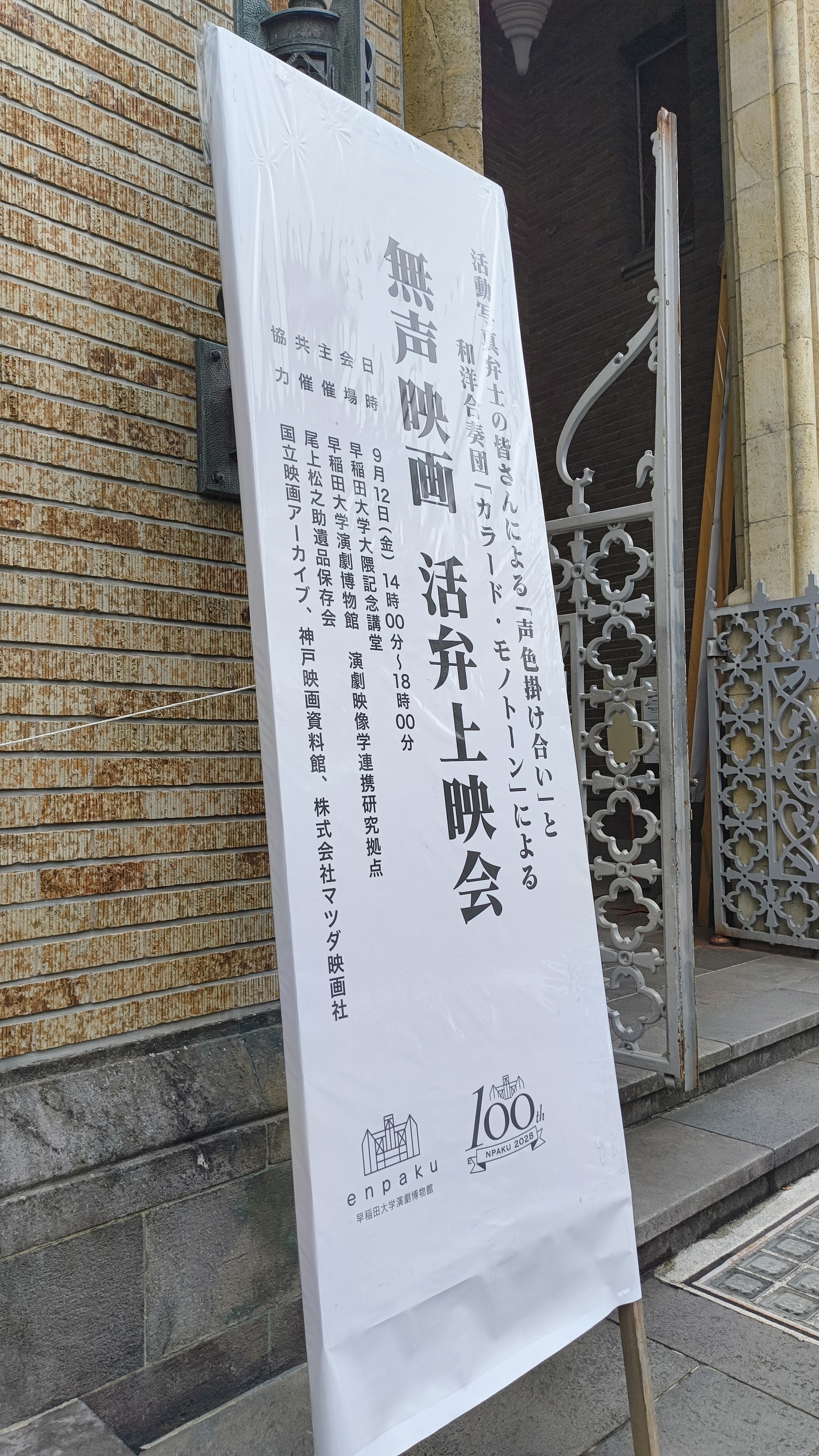 Auto-generated description: 「無声映画 活弁上映会」のポスターが建物の外に立てかけられている。