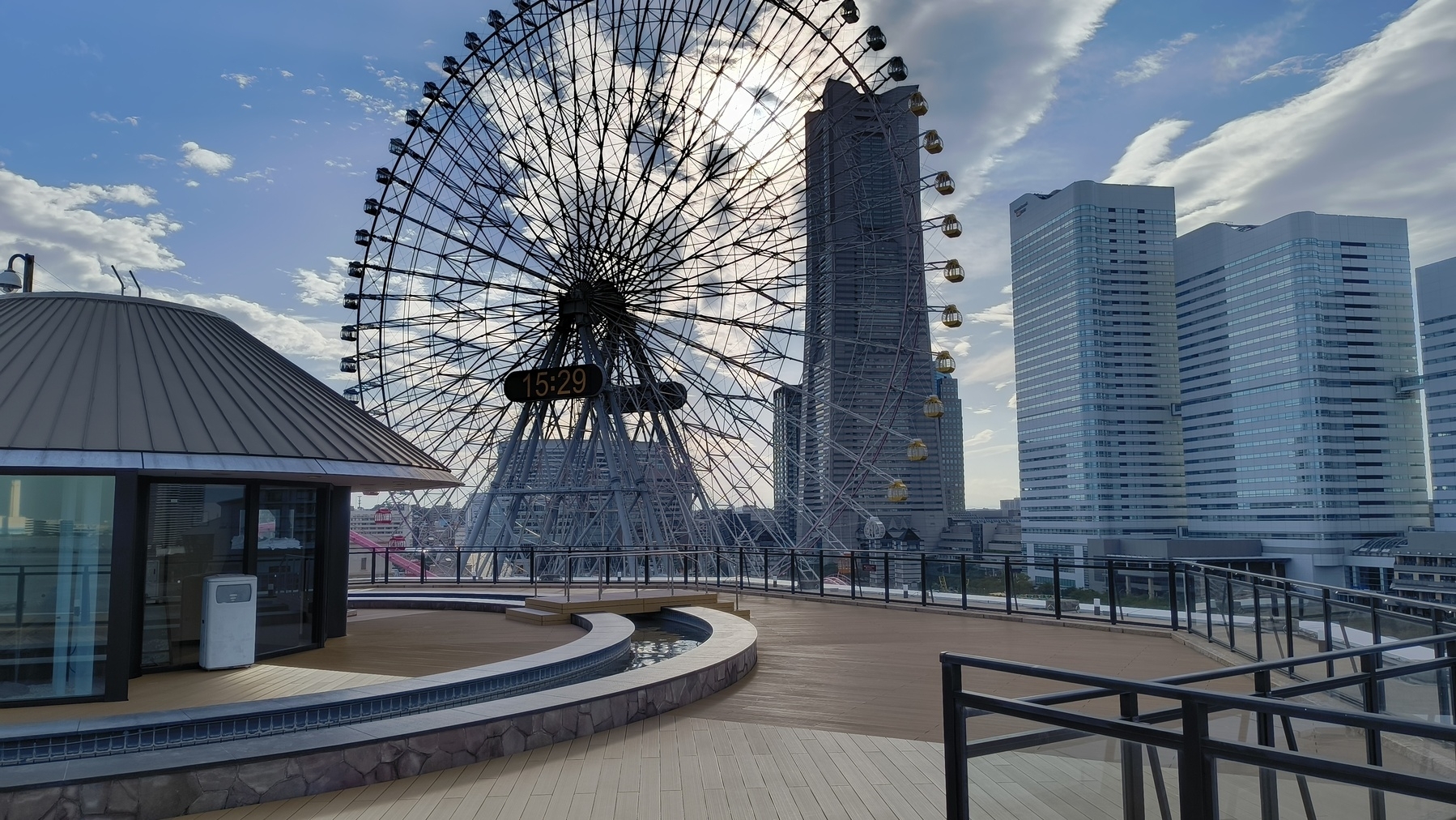 Auto-generated description: 観覧車と高層ビルが見える都市の屋上風景。