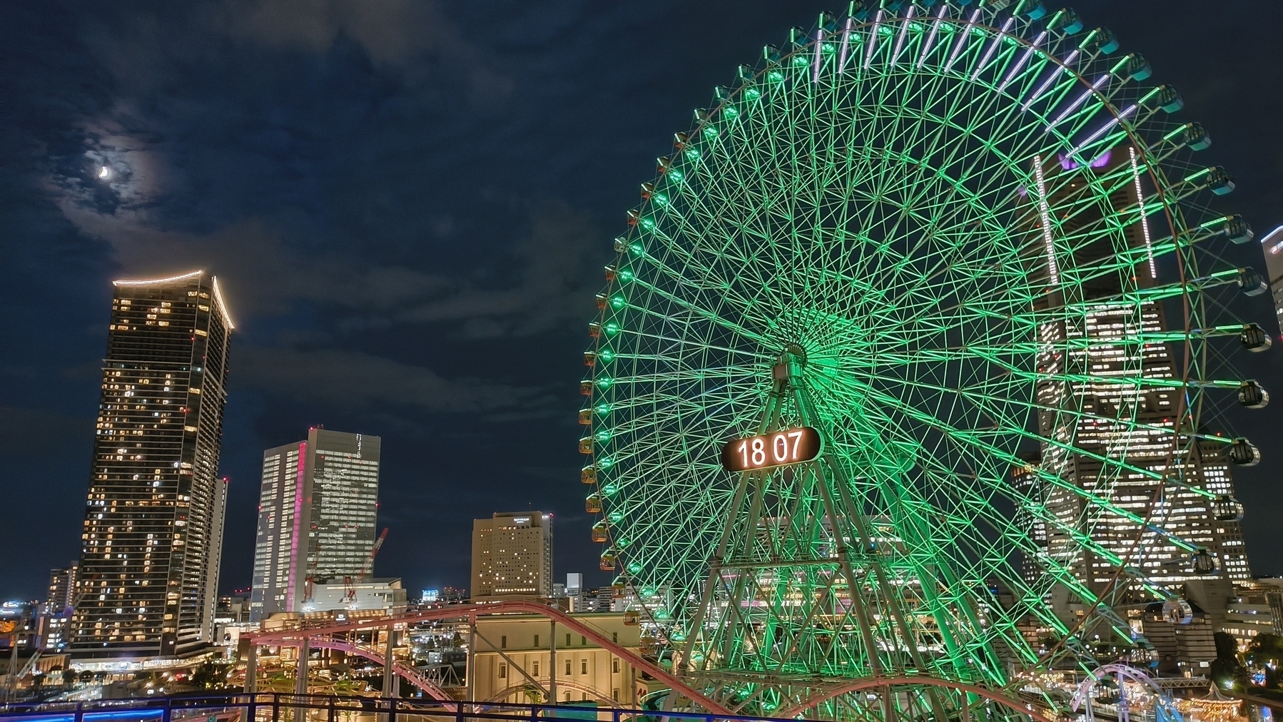Auto-generated description: 観覧車がライトアップされている夜の都会の風景。