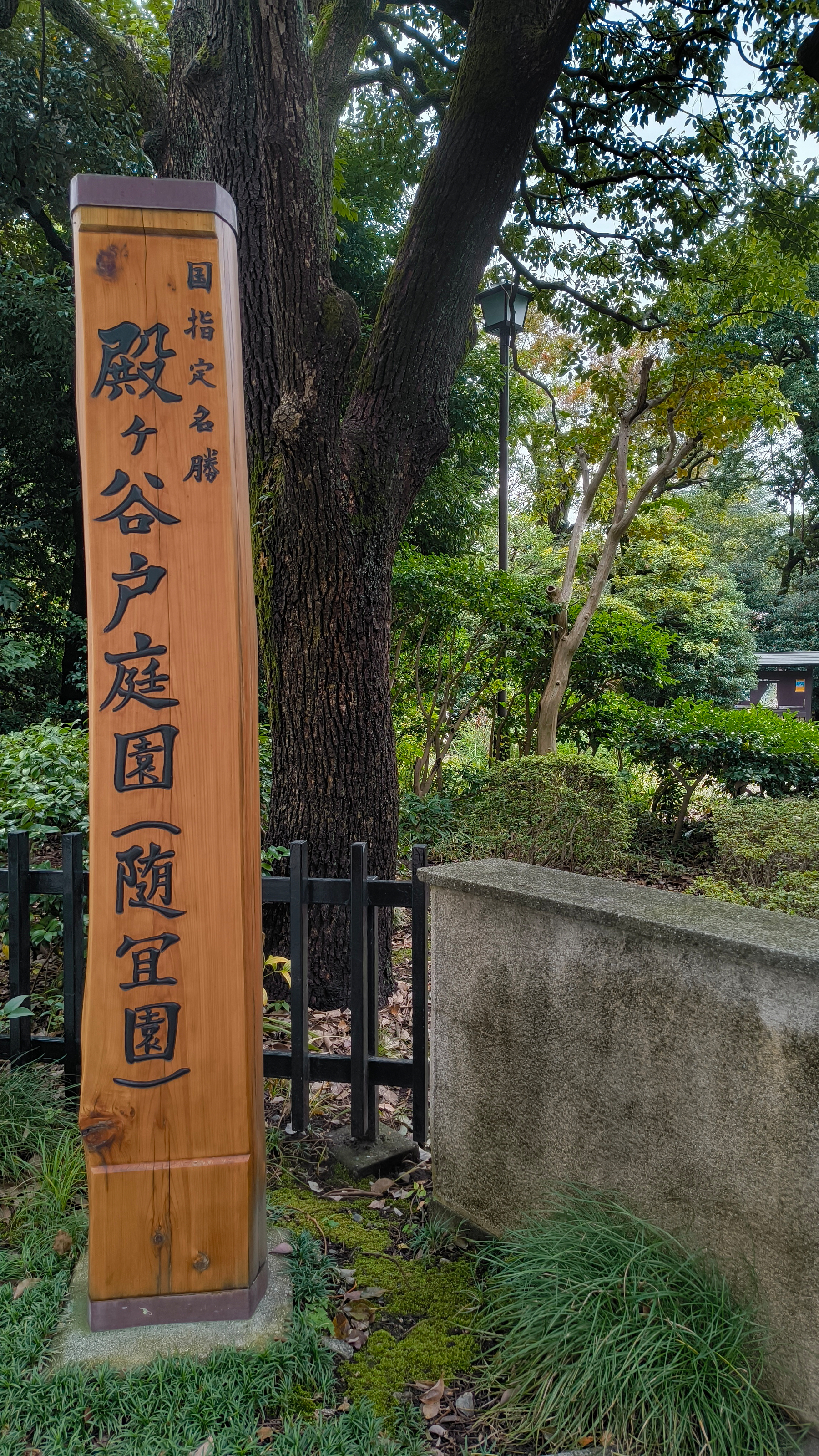 Auto-generated description: 国指定名勝「殿ヶ谷戸庭園附五園」の木製看板が立っている公園の一部。
