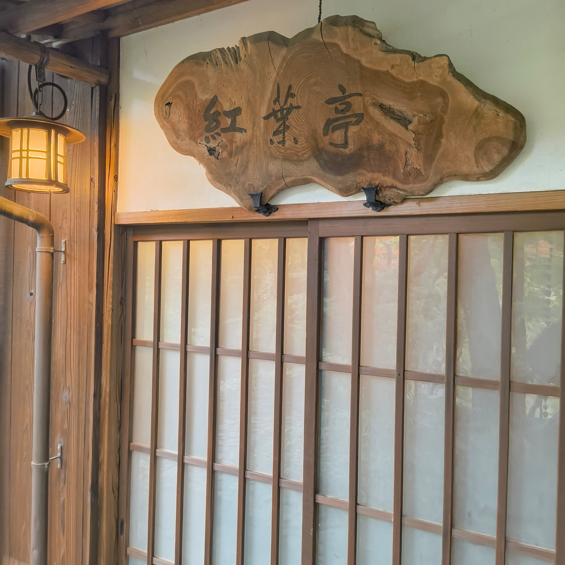 Auto-generated description: 木製の看板と和風の引き戸がある日本の伝統的な建築の一部。