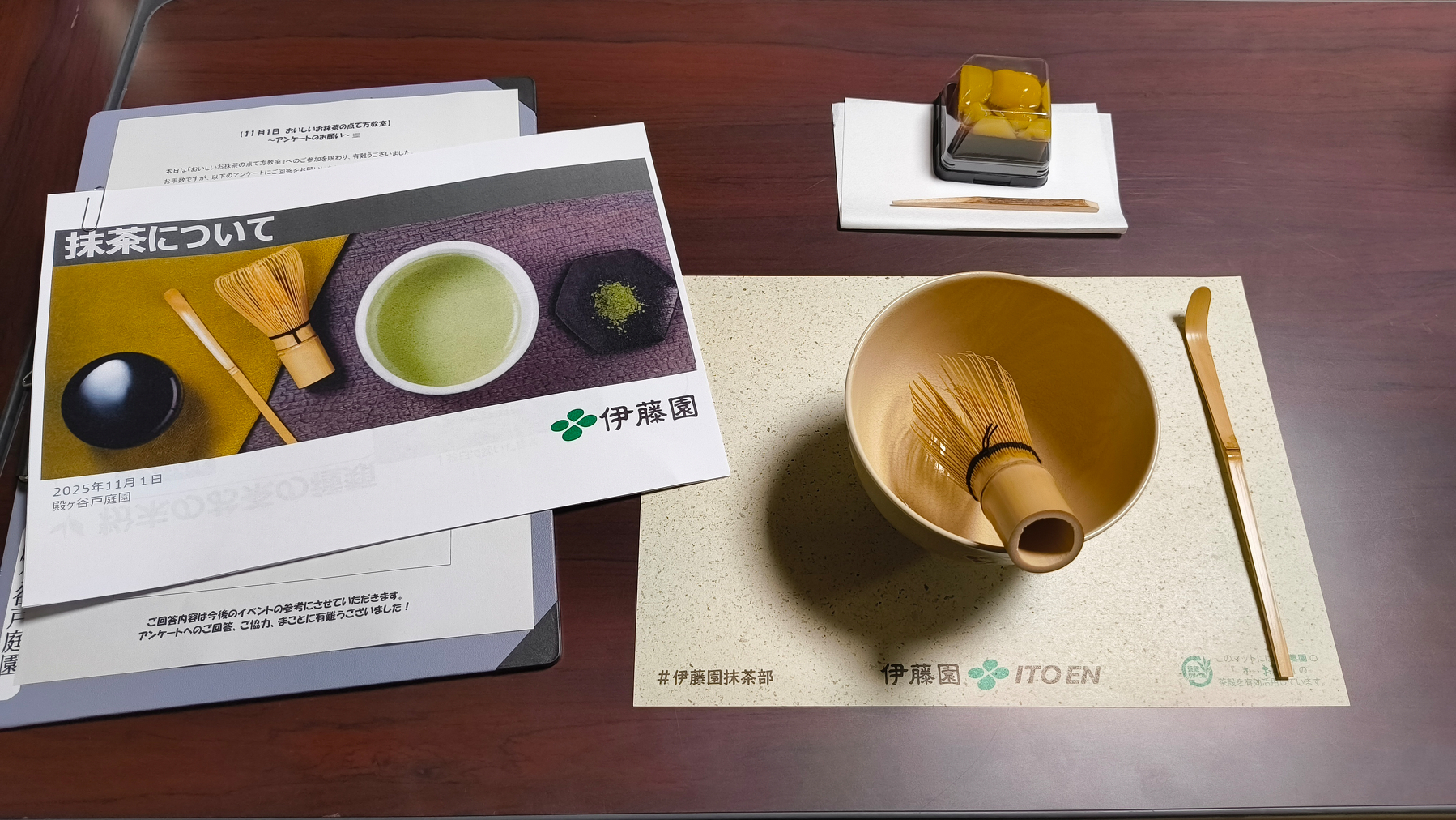 Auto-generated description: 茶道具と抹茶に関する冊子がテーブルに置かれている。