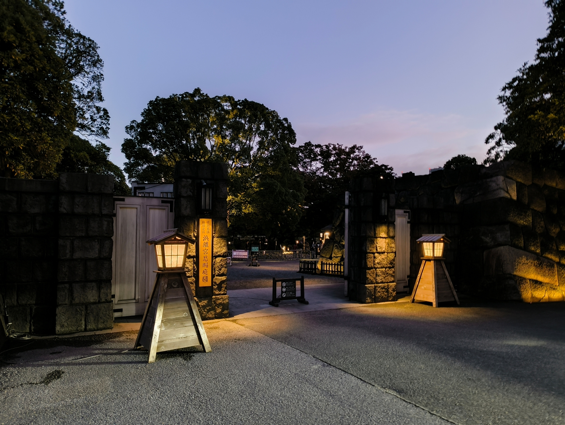 Auto-generated description: 歴史的な石造りの門と灯篭のある夕暮れの風景。