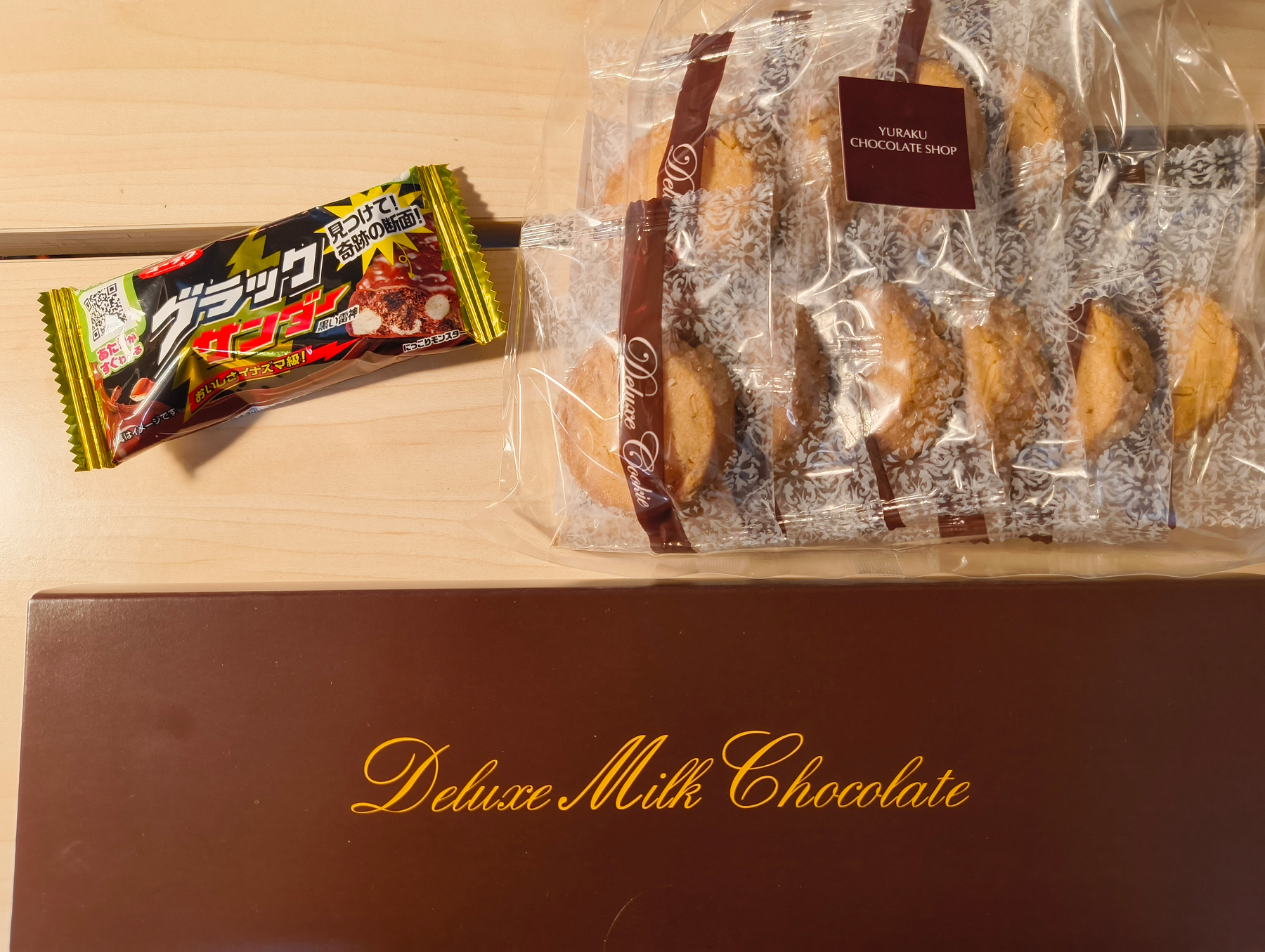 Auto-generated description: チョコレートバーと袋に入ったクッキーのセットが木製のテーブルの上に置かれています。
