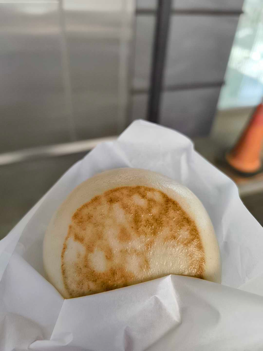 Auto-generated description: 白い紙に包まれた焼き目のついた饅頭です。