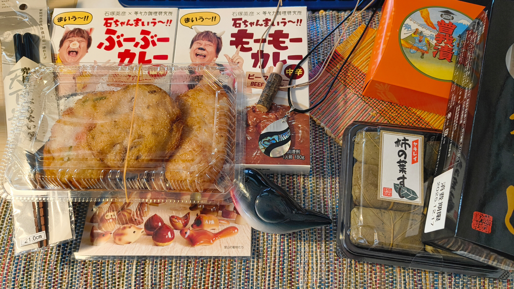 Auto-generated description: さまざまなパッケージ食品とカレーの箱、ネックレスや雑貨が並んでいるシーン。