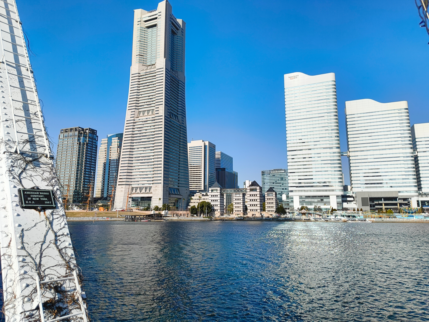 Auto-generated description: 横浜の美しい海岸線にある高層ビル群が青空の下にそびえ立っている。