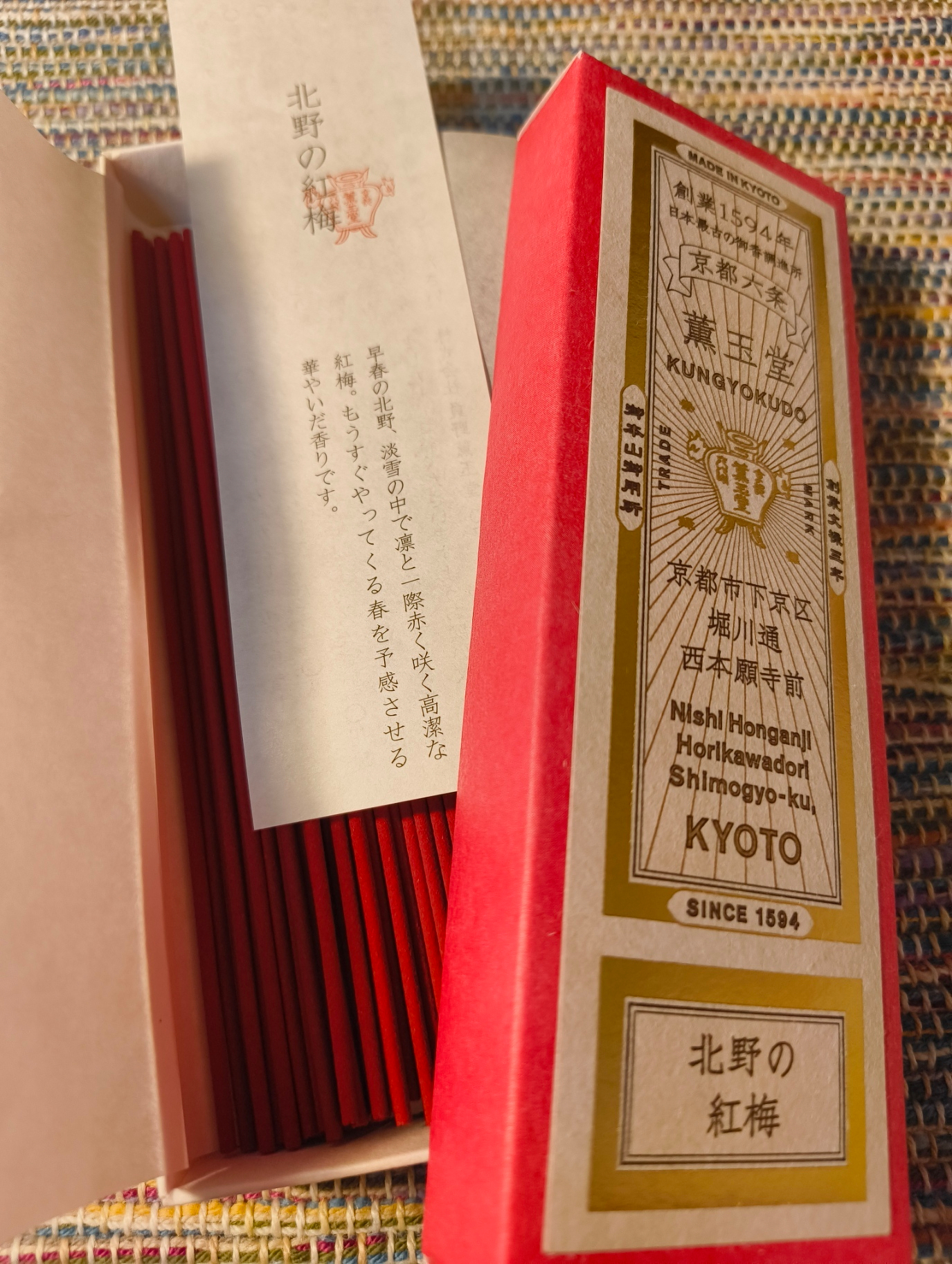 京都の「北野の紅梅」と書かれた伝統的なお線香の包装が開かれており、中に赤いお線香が並んでいる。