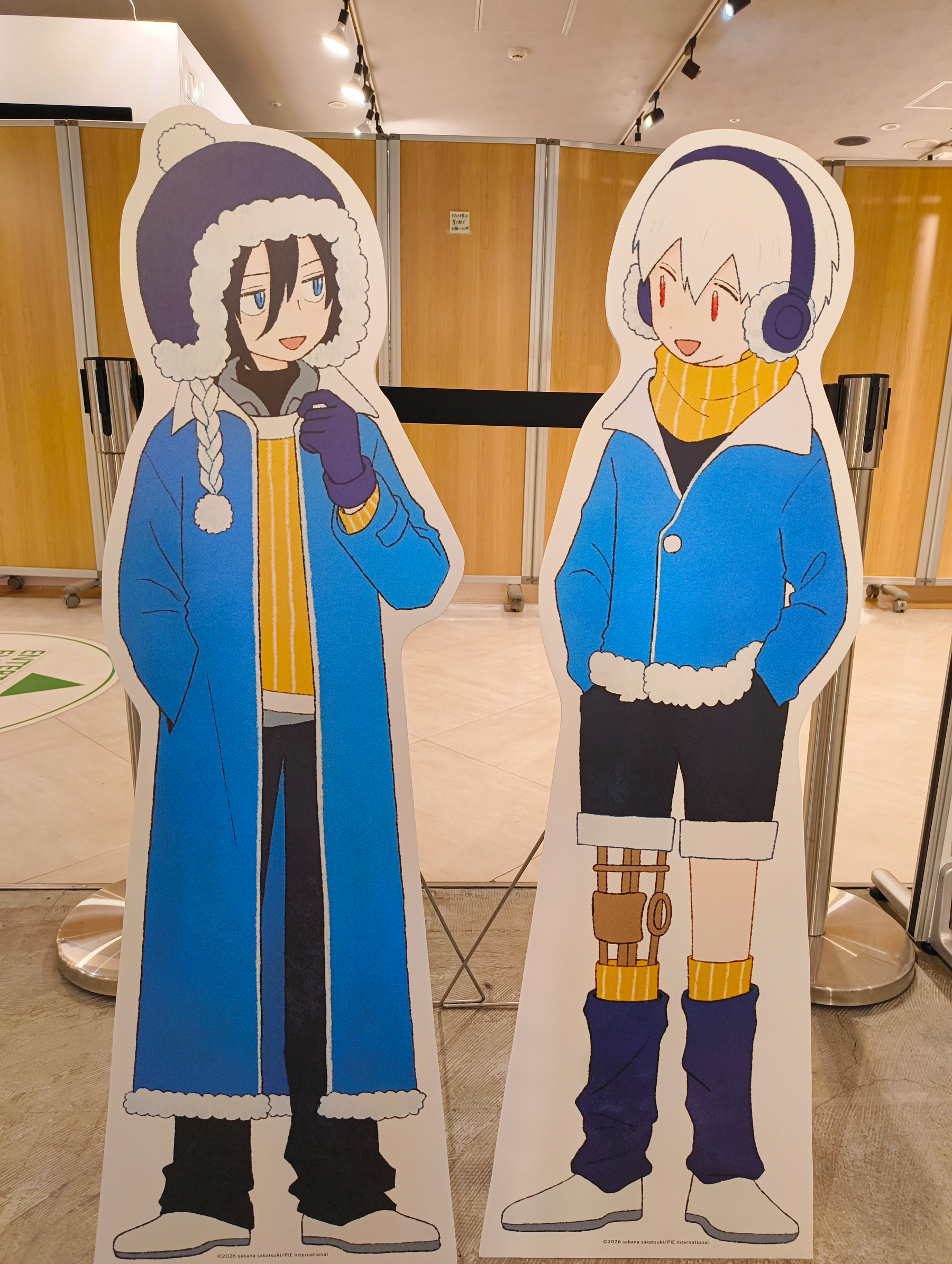 Auto-generated description: 青いコートを着た2人のキャラクターの立て看板が並んでいます。