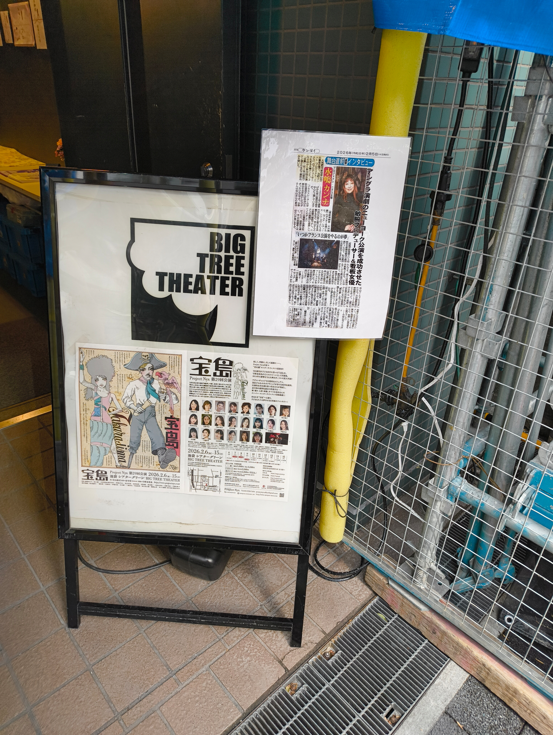 Auto-generated description: ビッグツリーシアターの看板に、ポスターと新聞記事が掲示されています。