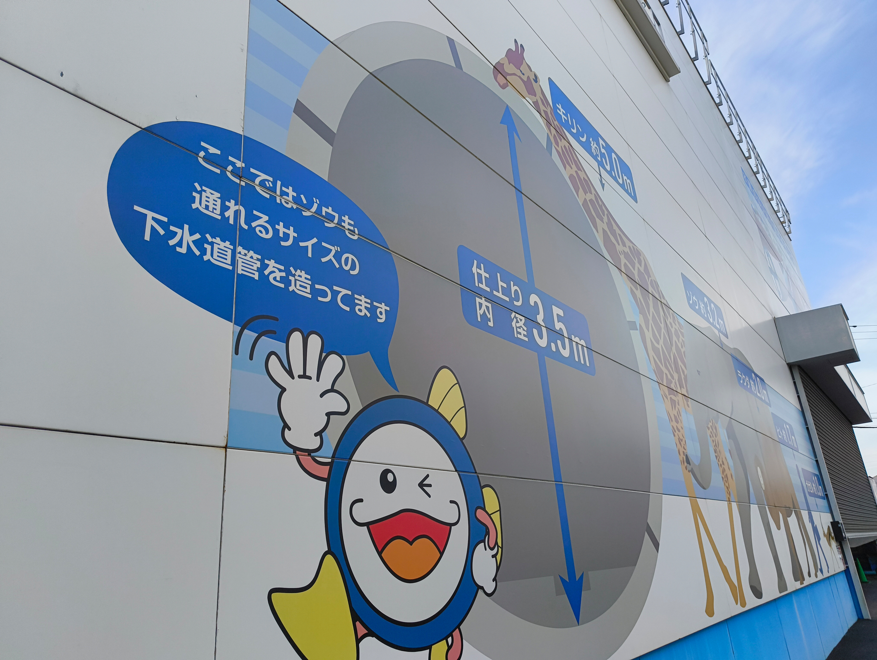 Auto-generated description: キャラクターが描かれた建物の壁に、下水道管についての説明が書かれたイラストが表示されています。
