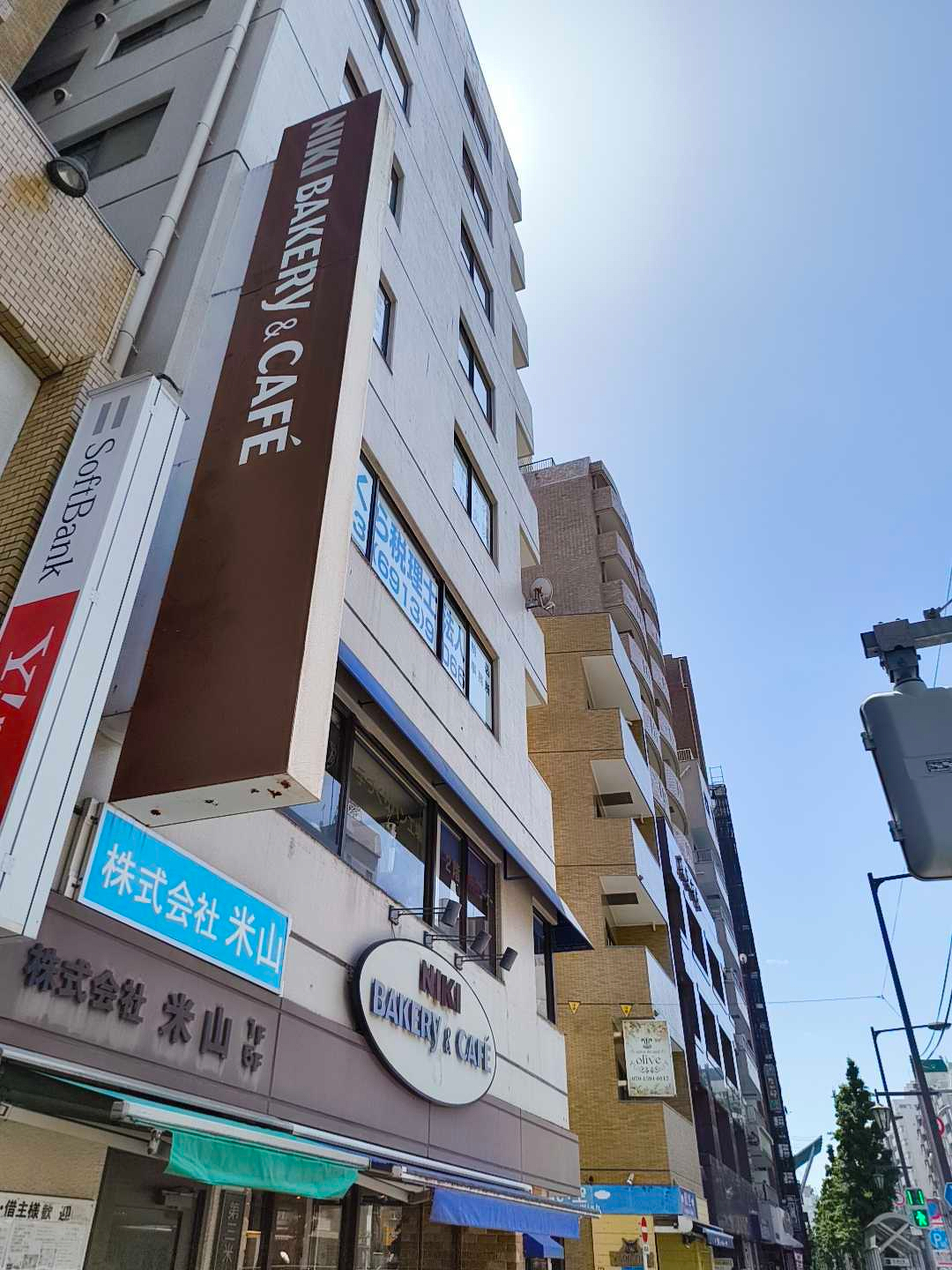 Auto-generated description: ビルの高いファサードには「NIKI BAKERY & CAFE」の看板が取り付けられています。