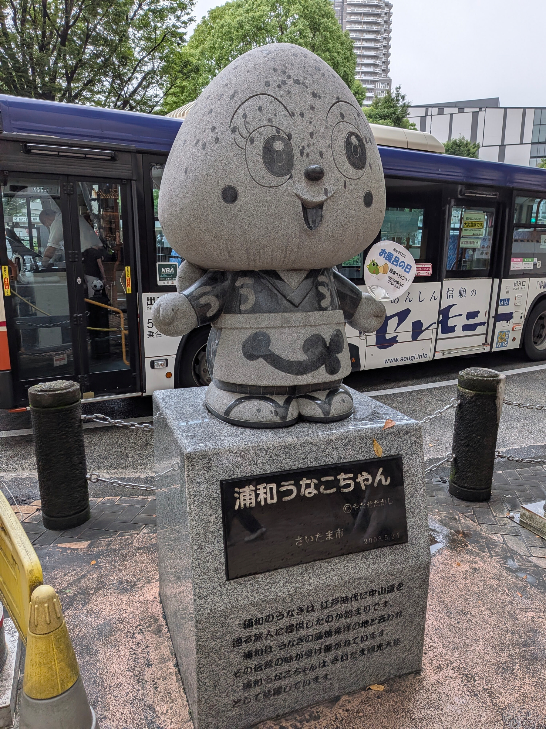 浦和うなこちゃんの石像がバス停の前に立っている。