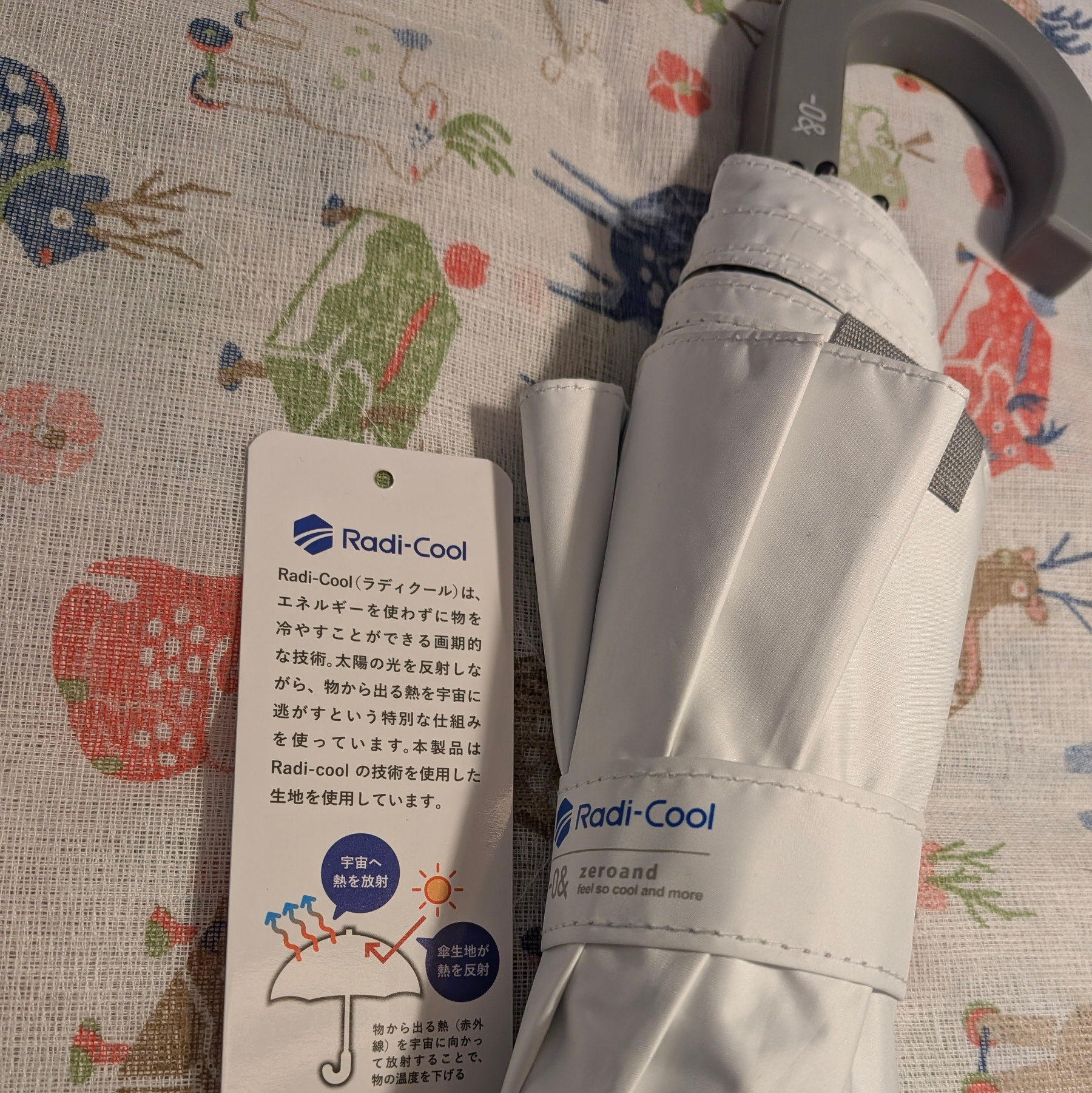 Radi-Cool技術を使用した紫外線と熱を反射する折りたたみ傘がテーブルクロスの上に置かれている。